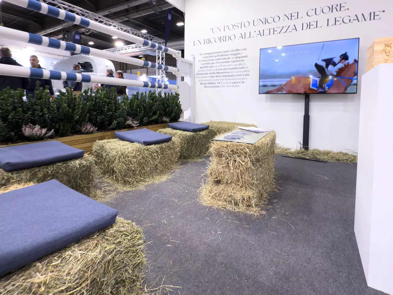 Angolo di sosta allestito con balle di fieno e cuscini blu allo stand La Gardesana
